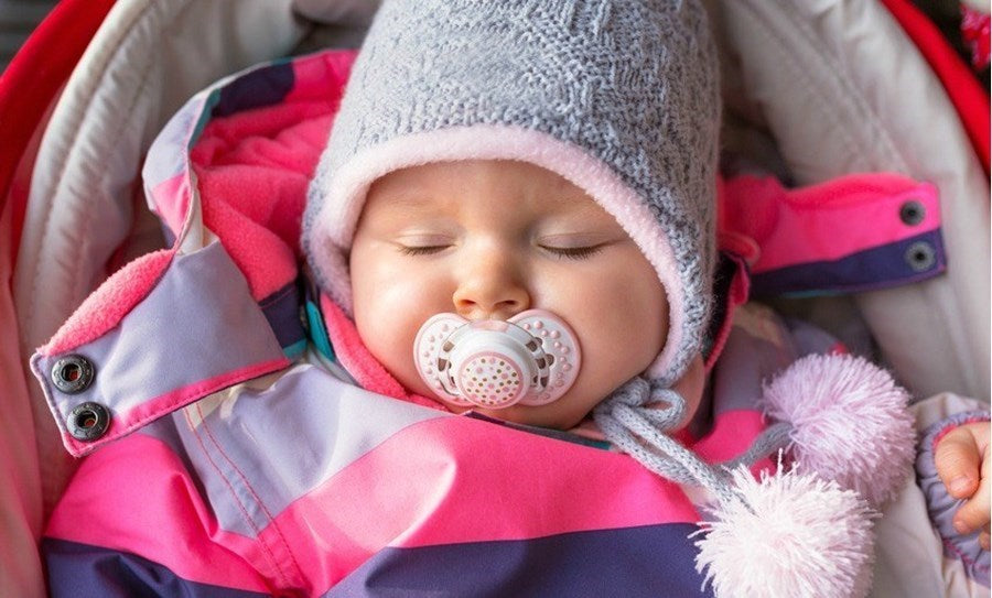 Photo d'un bébé bien couvert pendant l'hiver : bonnet, tétine, gigoteuse Babykare